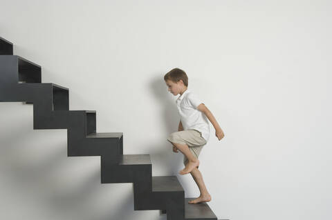 Deutschland, Junge (4-5 Jahre), der von der Treppe aufsteigt, lizenzfreies Stockfoto
