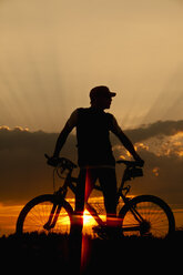 Deutschland, Niederbayern, Radfahrer mit Fahrrad bei Sonnenuntergang - MAEF002373