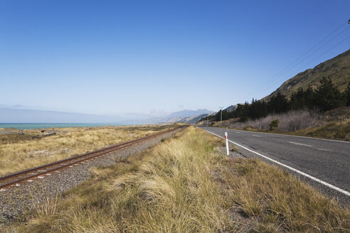Neuseeland, Südinsel, Canterburg, Kaikoura, Blick auf Hauptstraße mit Eisenbahnschienen und Meer im Hintergrund - GWF001211