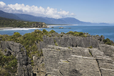 New Zealand, South Island, West Coast, View of Pancake Rocks with sea and mountains in background - GWF001290