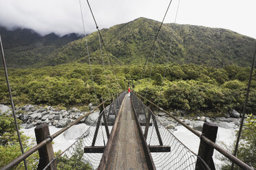 New Zealand, South Island, Woman crossing fox river through swing bridge - GWF001275