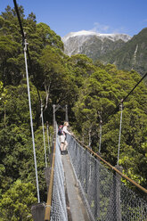 New Zealand, South Island, Woman standing on swing bridge - GWF001278