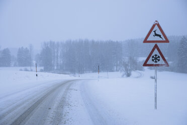 Germany, Bavaria, Moerlbach, View of country road covered in snow with sign board - TCF001340