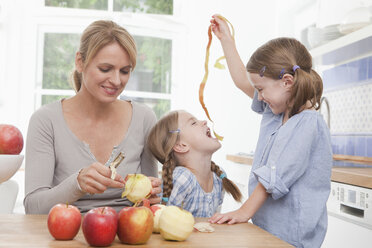 Germany, Munich, Mother peeling apple, girls (4-7) playing with peel - RBF000298