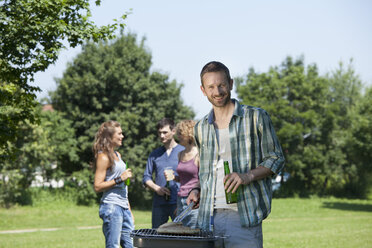 Deutschland, München, Mann kocht Essen und Freunde im Hintergrund - LDF000863