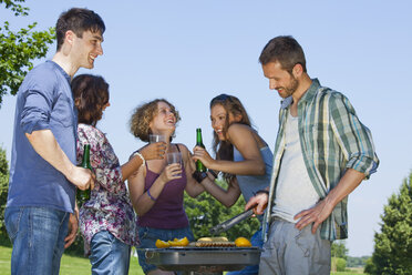 Germany, Munich, Man cooking food and friends smiling - LDF000861