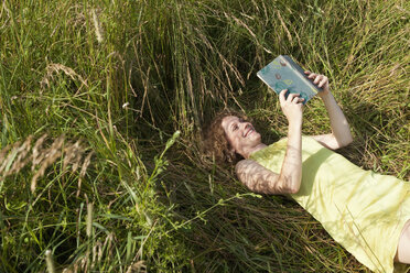 Deutschland, München, Frau liegt im Gras und liest ein Buch - LDF000889