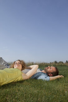 Deutschland, München, Mann und Frau liegen im Gras und lächeln - LDF000885