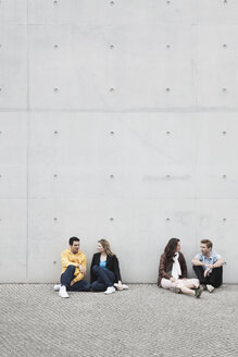 Deutschland, Berlin, Mann und Frau sitzen an der Wand und reden - WESTF015183