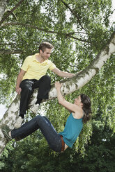 Deutschland, Berlin, Mann sitzt auf Baum und Frau hängt - WESTF015160