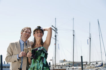 Germany, Hamburg, Couple looking away and drinking champagne, smiling - WESTF015240