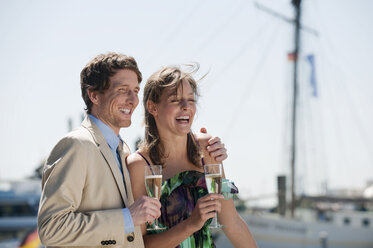 Germany, Hamburg, Couple looking away and drinking champagne, smiling - WESTF015249