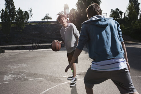 Deutschland, Berlin, Teenager spielen Basketball auf einem Spielplatz - WESTF015325