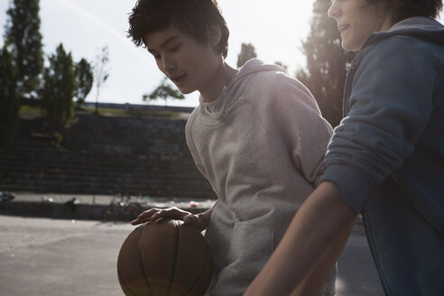 Deutschland, Berlin, Teenager spielen Basketball auf einem Spielplatz - WESTF015330