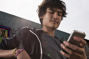 Germany, Berlin, Teenage boy using mobile phone - WESTF015339