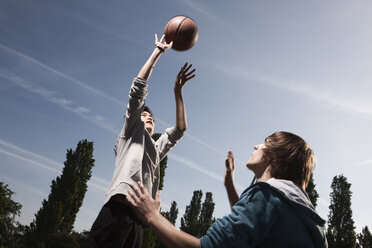 Deutschland, Berlin, Teenager-Jungen Basketball auf dem Spielplatz - WESTF015346