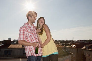 Germany, Bavaria, Munich, Young couple enjoying beer on rooftop - SKF000389