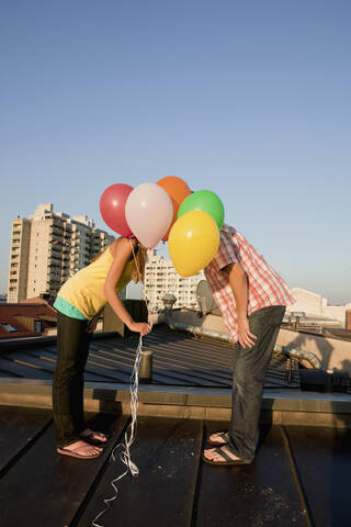 Deutschland, Bayern, München, Junges Paar mit Luftballons auf dem Dach, lizenzfreies Stockfoto
