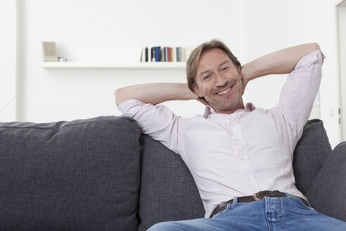 Mann entspannt auf Sofa, lächelnd - LDF000897