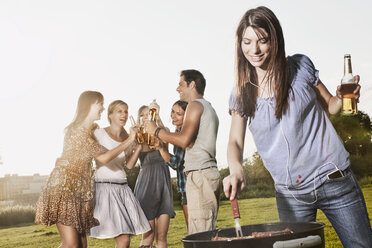 Deutschland, Köln, Frau beim Grillen mit Freunden im Hintergrund - JOF000142