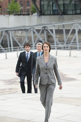 Deutschland, Hamburg, Geschäftsfrau geht mit Geschäftsleuten im Hintergrund - WESTF015413