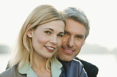 Germany, Hamburg, Business couple embracing at harbour - WESTF015457