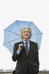 Germany, Hamburg, Businessman with umbrella, looking away - WESTF015459