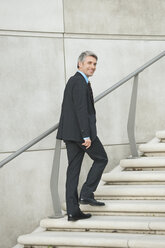 Germany, Hamburg, Businessman climbing steps, smiling, portrait - WESTF015479