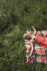 Germany, Dortmund, Young woman resting on grass - SKF000251