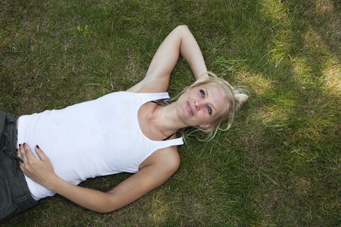 Germany, Dortmund, Young woman resting on grass, smiling - SKF000254