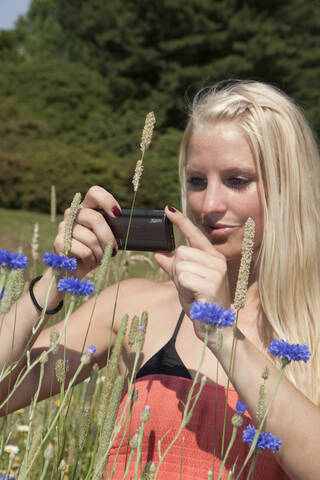 Deutschland, Dortmund, Junge Frau, die ein Bild mit ihrem Mobiltelefon aufnimmt, lizenzfreies Stockfoto