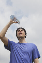 Germany, Cologne, Young man pouring water on himself - SKF000361