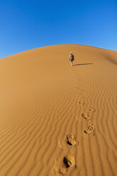 Africa, Namibia, Namib Naukluft National Park, Man walking on sand in the namib desert - FOF002478