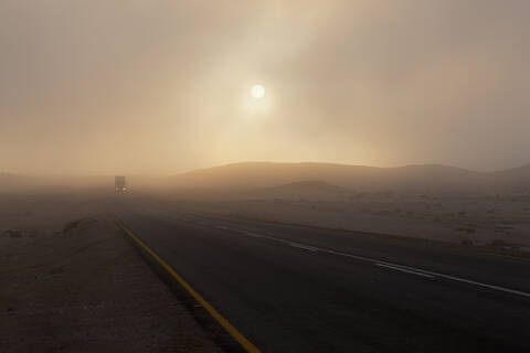 Afrika, Namibia, Namib-Wüste, Swakopmund, Blick auf Fahrzeug auf nebliger Straße in der Morgendämmerung, lizenzfreies Stockfoto