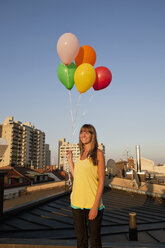 Deutschland, Bayern, München, Frau steht auf dem Dach und hält Luftballons - SKF000403