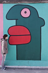 Deutschland, Berlin, Junge Frau steht an der Berliner Mauer - WVF000053