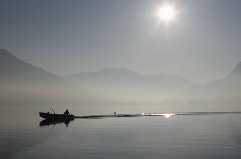 Österreich, Mondsee, Blick auf Fischerboot im See bei nebligem Morgen, lizenzfreies Stockfoto