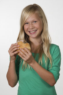 Mädchen (12-13 Jahre) mit Sandwich lächelnd, Porträt - WWF001685