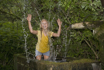 Österreich, Mondsee, Mädchen (12-13 Jahre) spielt mit Wasser im Wassertrog - WWF001624