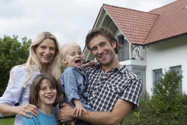 Germany, Munich, Family standing in front of house, smiling, portrait - RBF000399