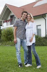 Germany, Munich, Couple standing in front of house, smiling, portrait - RBF000323