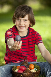 Deutschland, Junge (10-11 Jahre) lächelnd mit Ostereierkorb, Porträt - MAEF002515
