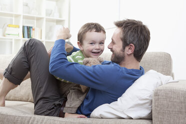 Germany, Bavaria, Munich, Father and son (2-3 Years) having fun on sofa - RBF000332