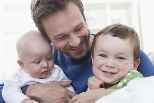 Deutschland, Bayern, München, Vater mit seinen Kindern auf Sofa, lächelnd - RBF000339