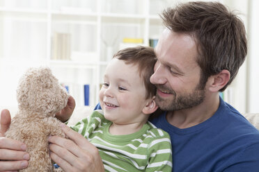 Deutschland, Bayern, München, Vater und Sohn (2-3 Jahre) mit Teddybär, lächelnd - RBF000340