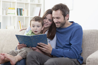 Germany, Bavaria, Munich, Parents reading book with son (2-3 Years) in living room - RBF000413