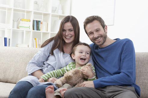 Deutschland, Bayern, München, Familie auf Sofa im Wohnzimmer, lächelnd - RBF000343