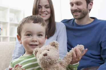 Germany, Bavaria, Munich, Family on sofa in living room, smiling - RBF000344