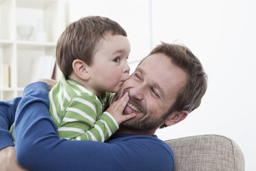 Deutschland, Bayern, München, Sohn (2-3 Jahre) küsst seinen Vater, lächelnd - RBF000350