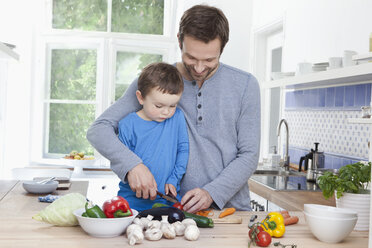 Germany, Bavaria, Munich, Father and son (2-3 Years) chopping tomato - RBF000361
